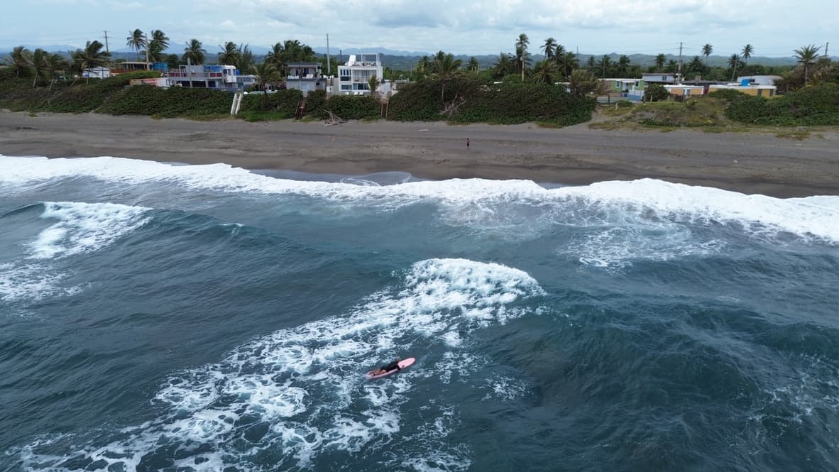 Ramon among the waves, with Arenas Negra just beyond the black-sand beach